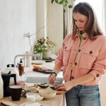 A woman slices an avocado in a bright, modern kitchen with natural light.