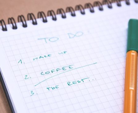 Handwritten to-do list on graph paper notebook with pen. Ideal for organizing tasks.